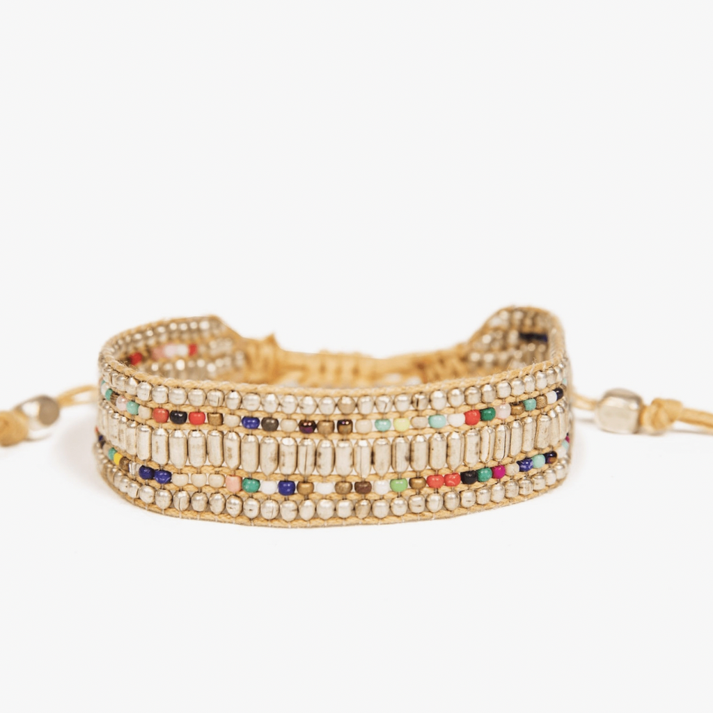 Photograph of a multi-strand beaded bracelet featuring rows of silver-colored round and tube beads interspersed with vibrant colorful seed beads on a light tan cord against a clean white background