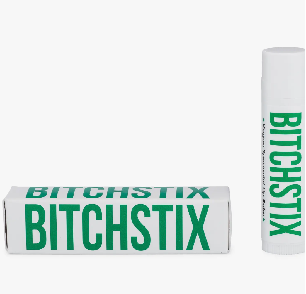 Bitchstix vegan spearmint lip balm in a white rectangular box and a matching white cylindrical tube, both prominently featuring the brand name in bold green lettering on a clean white background